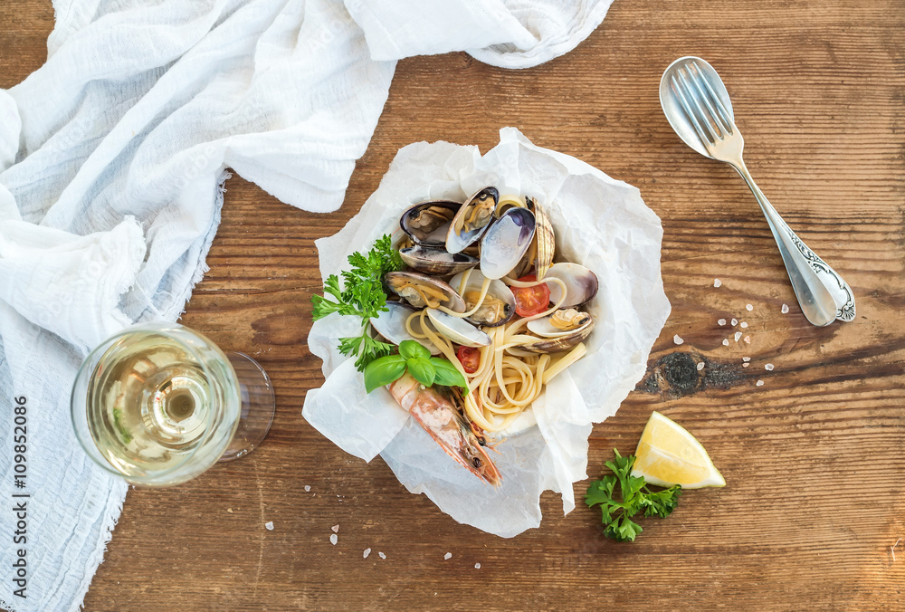 Seafood pasta. Spaghetti with clams and shrimps in bowl, glass of white wine