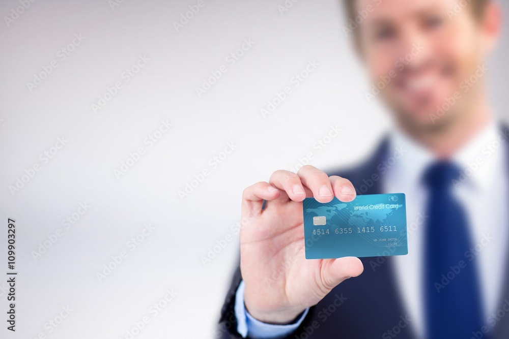 Composite image of happy businessman showing a creditcard