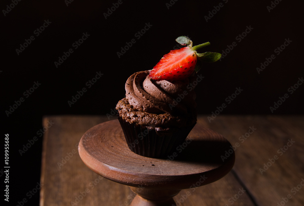 Chocolate cupcakes with strawberry and chocolate on a wooden table.