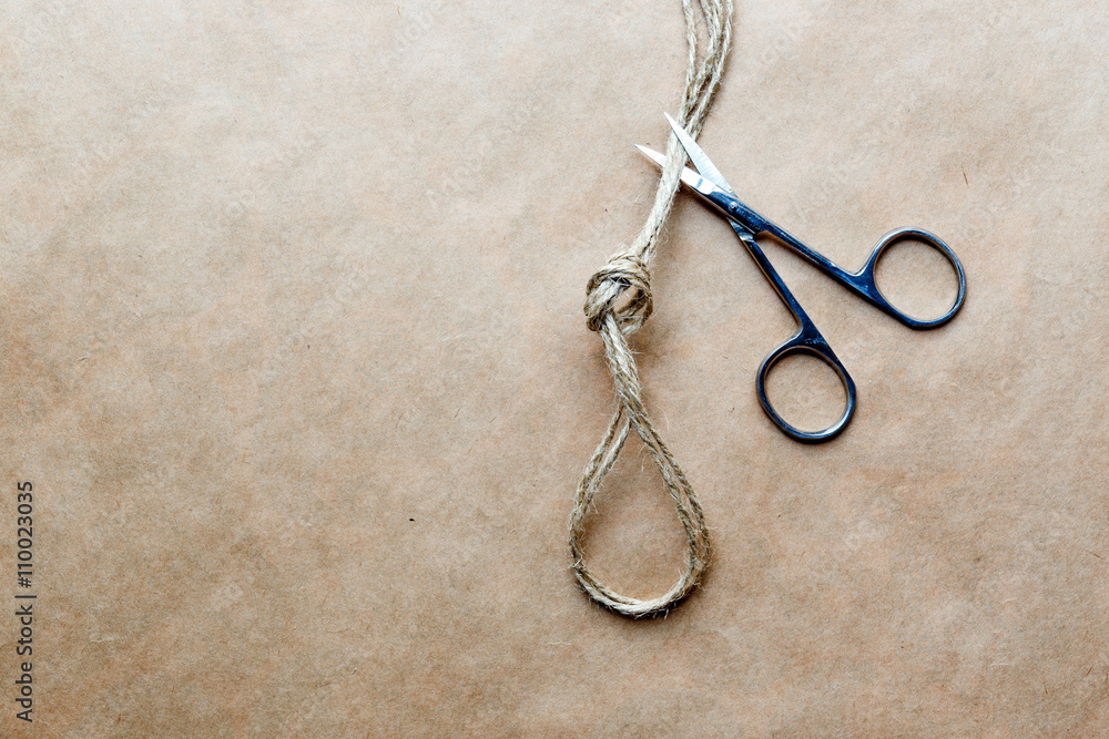 concept scissors cut knot on rope at background kraft paper