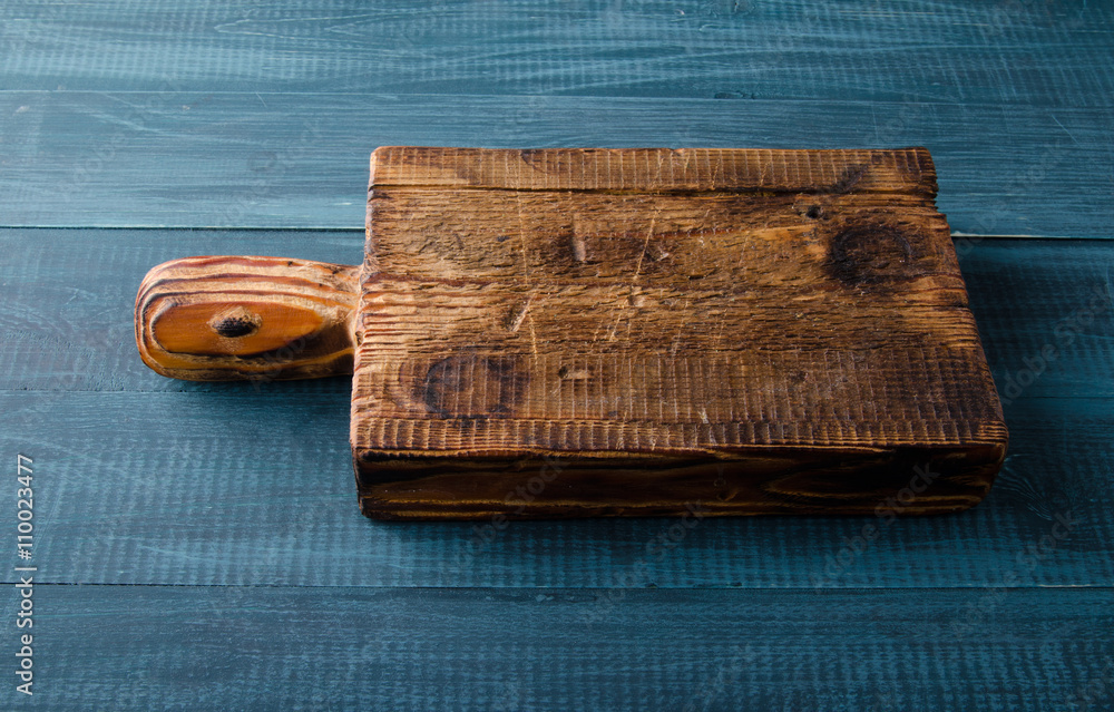 Wooden board on a blue wooden table. Top view