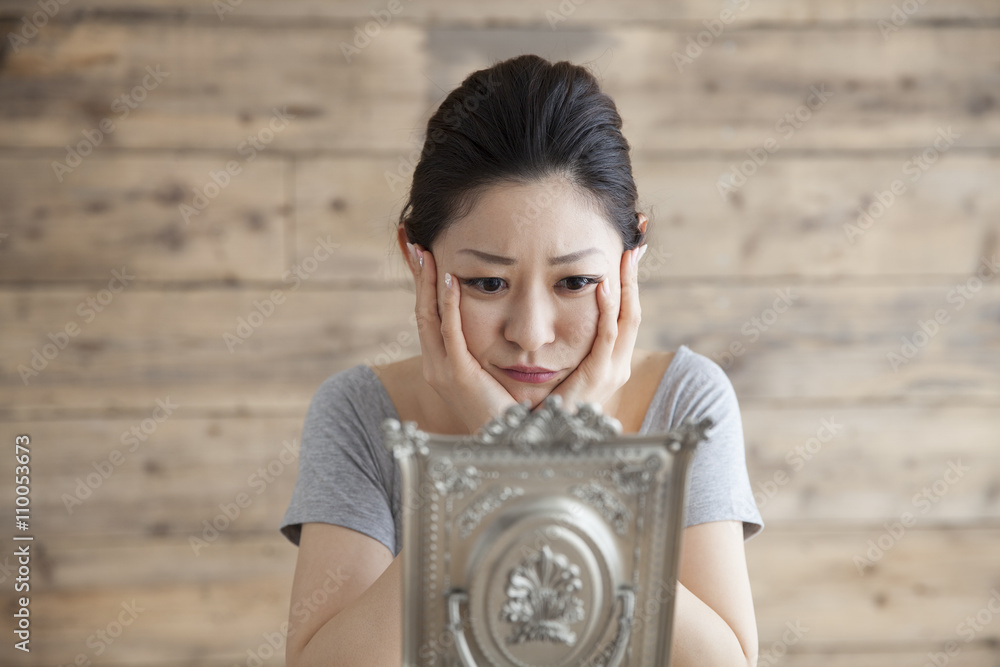 年轻女性一边照镜子一边思考