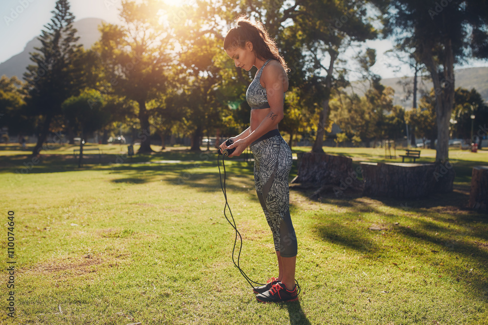 Fit young woman with skipping rope outdoors at the park