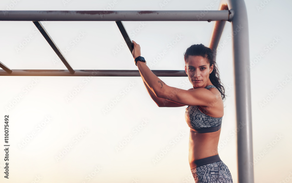 Fitness woman training outdoors on monkey bars