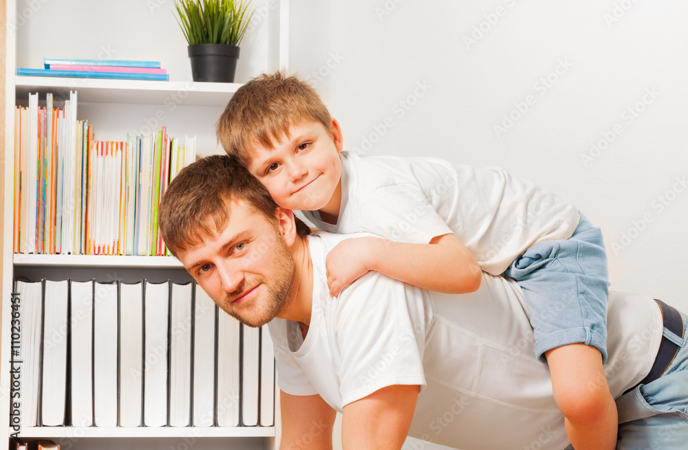 Close-up picture of boy riding on fathers back