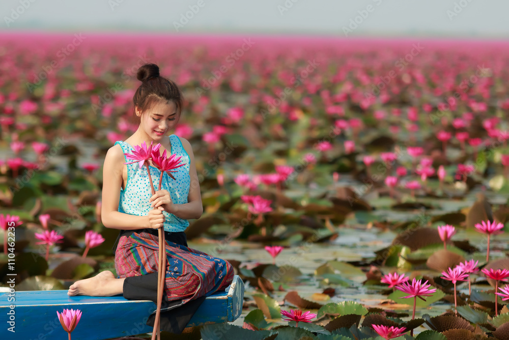 Beautiful girl sitting in boat in the lotus field