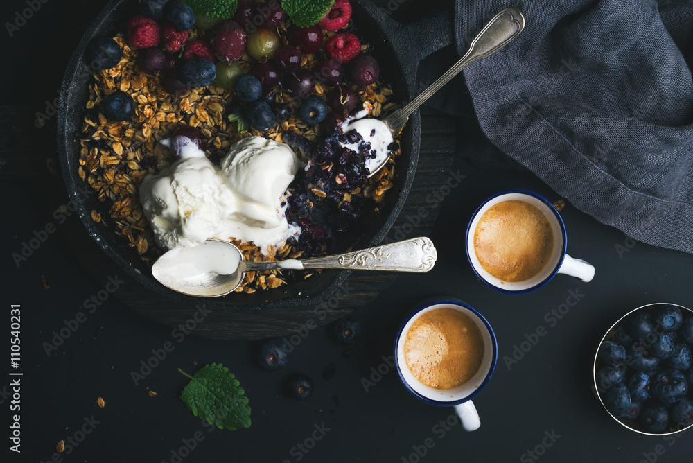 Healthy breakfast. Oat granola crumble with fresh berries, seeds and ice-cream in iron skillet pan o