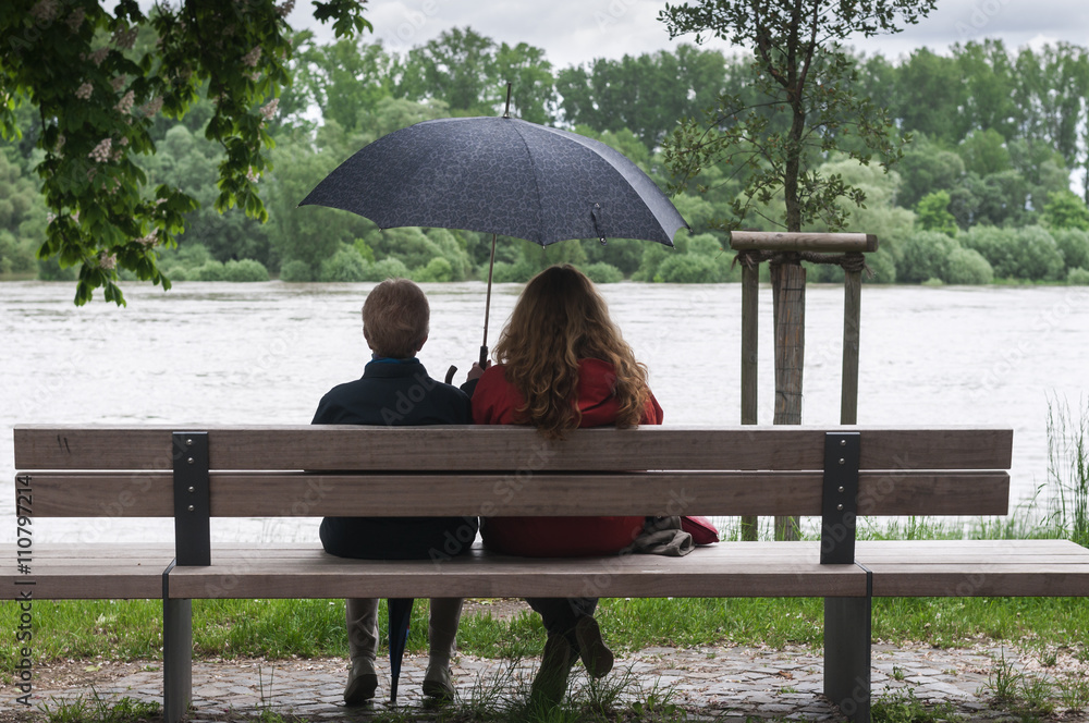 Frauen mit Regenschirm auf einer Bank / Aufnahme zeigt zwei Frauen, unterschiedlichen Alters sitzend