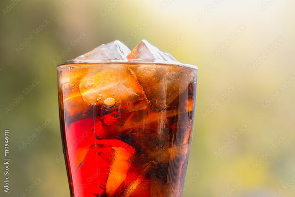 cola with in glass with ice cubes, nature background