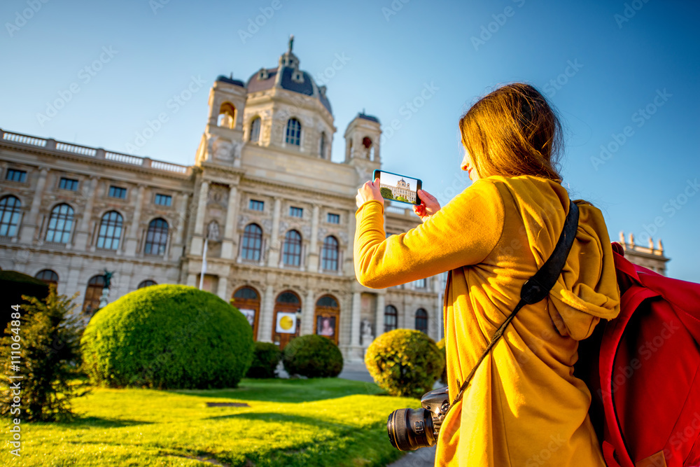 Young female tourist photographing with smart phone museum of Art History in Vienna.