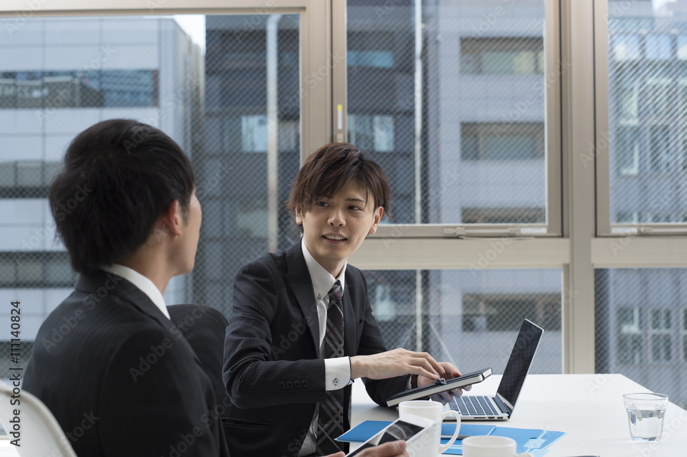 Two men are talking in a bright office