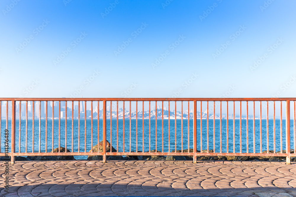 red steel railing near sea with cityscape and skyline of san fra