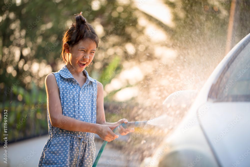 快乐的亚洲女孩在家泼水和阳光下洗车