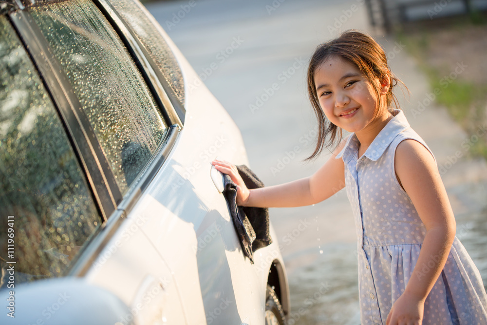 Happy Asian girl washing car on water splashing and sunlight at home