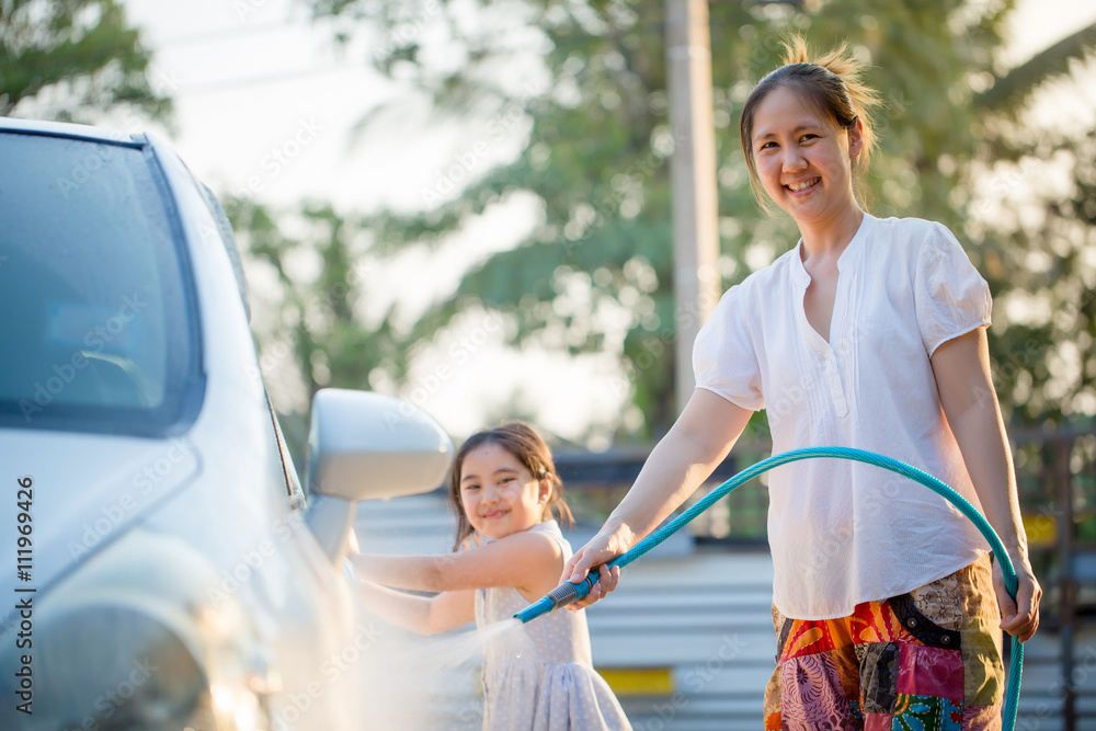 Happy Asian girl helping her mother washs car at home