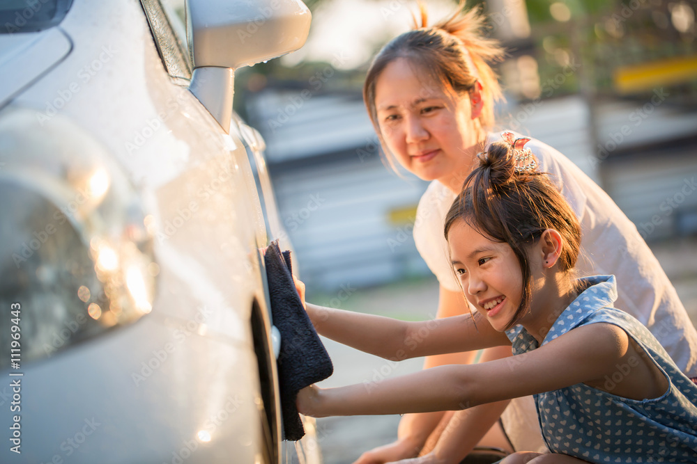 Happy Asian girl helping her mother washs car at home