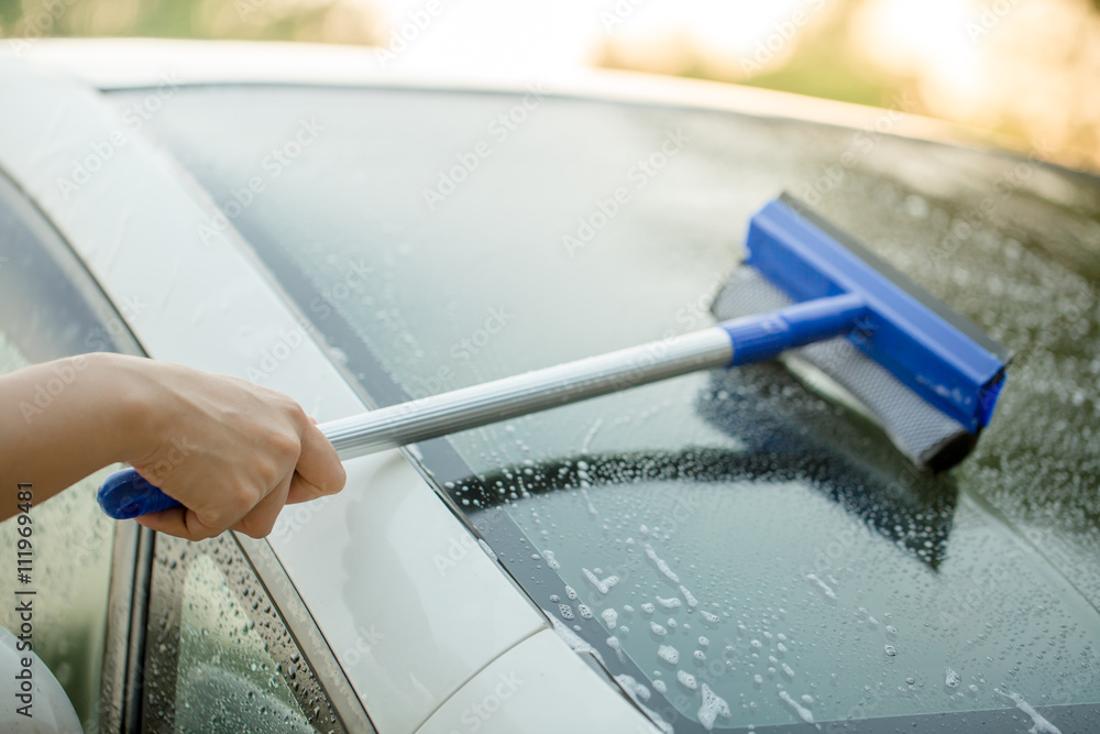 People cleaning car glass using cleaning brush