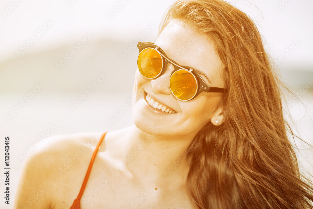 Young woman on the beach in hot summer sun light