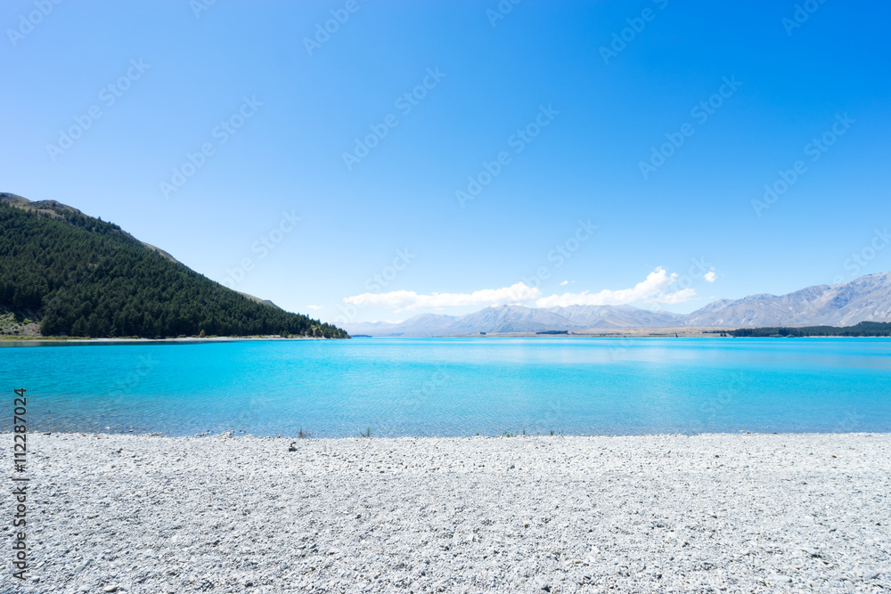 clear tranquil water and green hill in blue sky