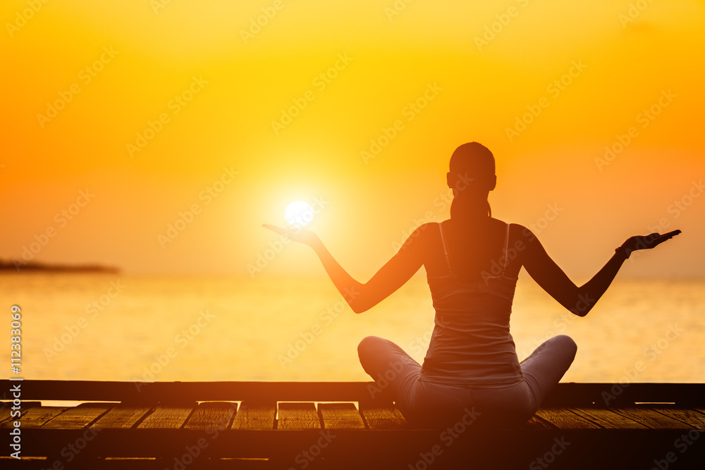 Silhouette of young woman practicing yoga