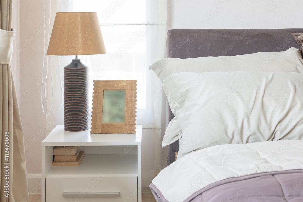 white pillow on bed with picture frame and lamp