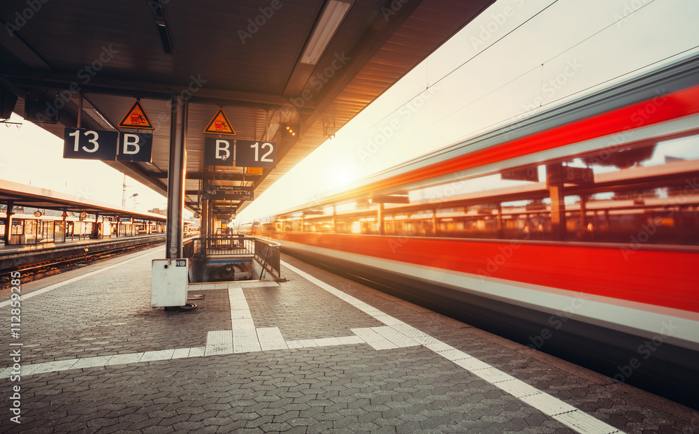 High speed red passenger train on railroad track in motion at sunset. Blurred commuter train. Railwa