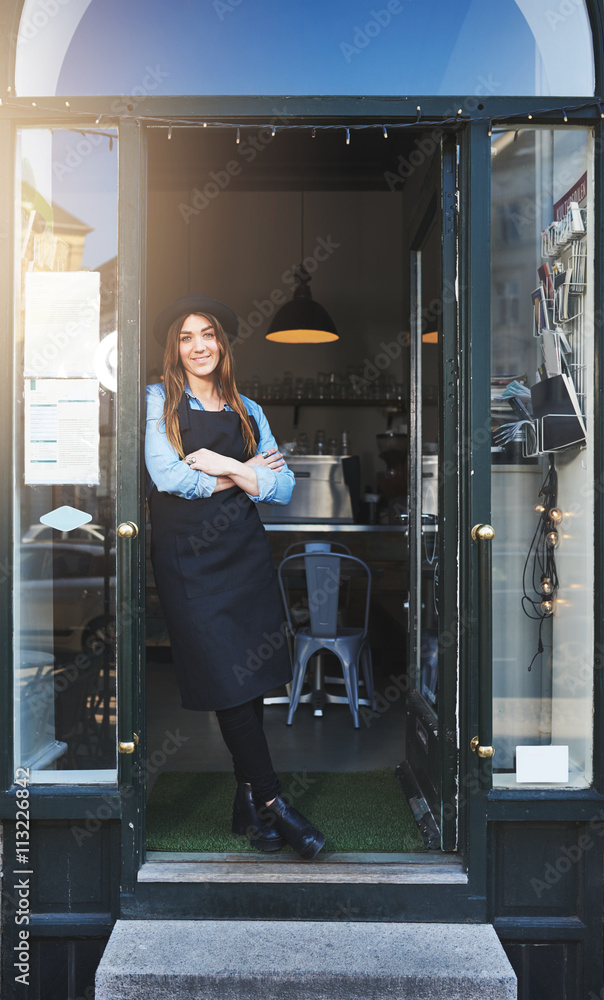 Cheerful barista leaning against doorway in cafe