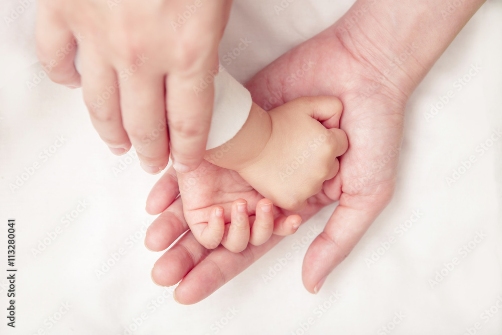 Baby hand gently holding adults finger (Soft focus and blurry)