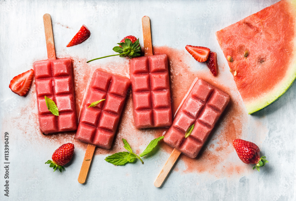 Strawberry watermelon ice cream popsicles with mint over steel tray background