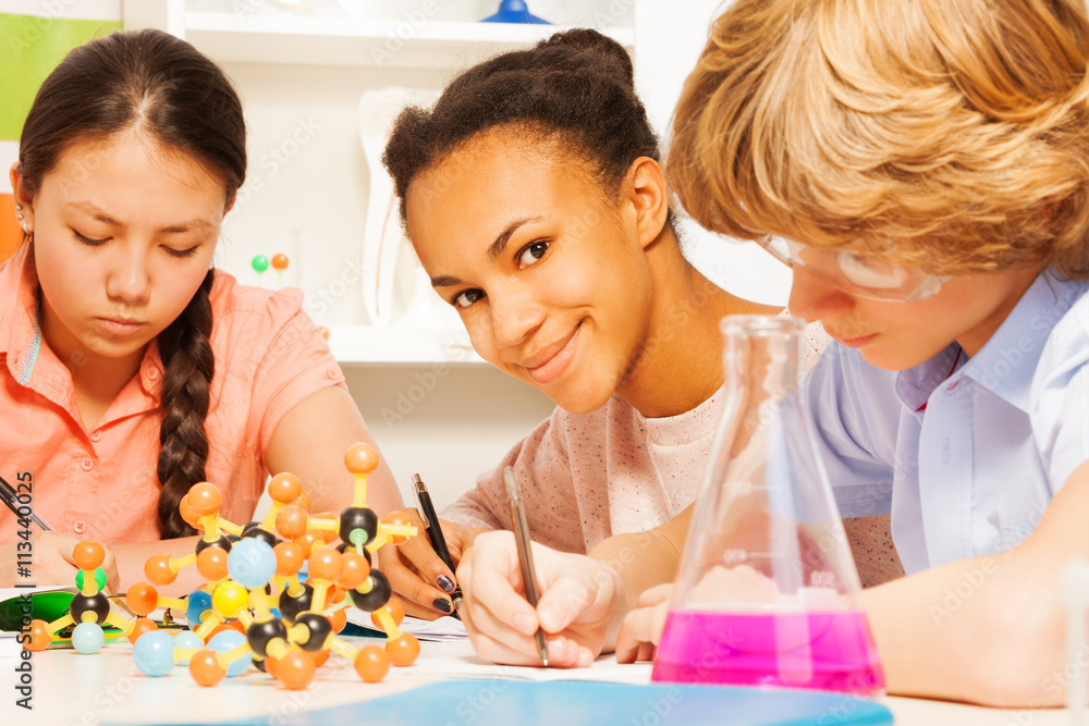 Three students writing chemical formula at class