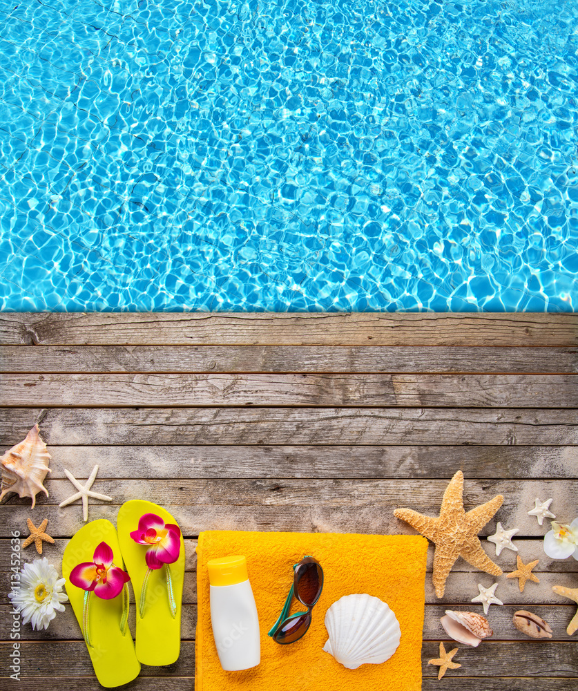 Beach accessories on wooden background with pool