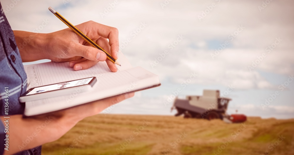 Composite image of cropped image of businessman writing with pencil on book