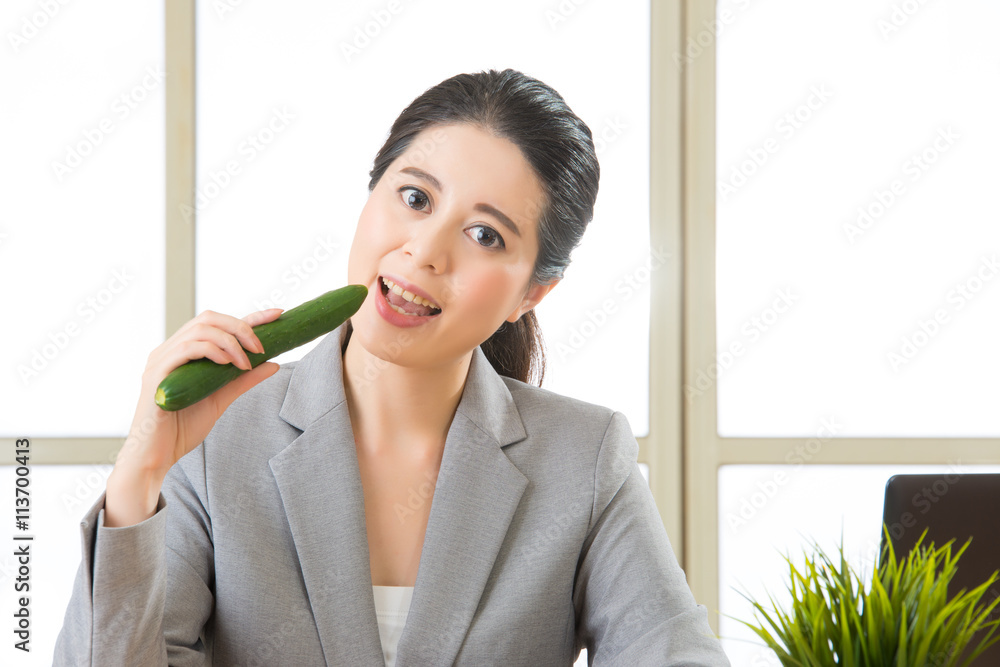 Young asian businesswoman eating healthy snack, cucumber