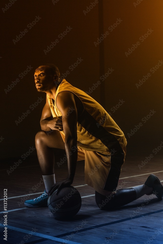 Portrait of basketball player with a knee on the floor 