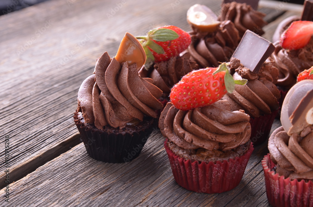 Chocolate cupcakes with strawberry on a wooden table.