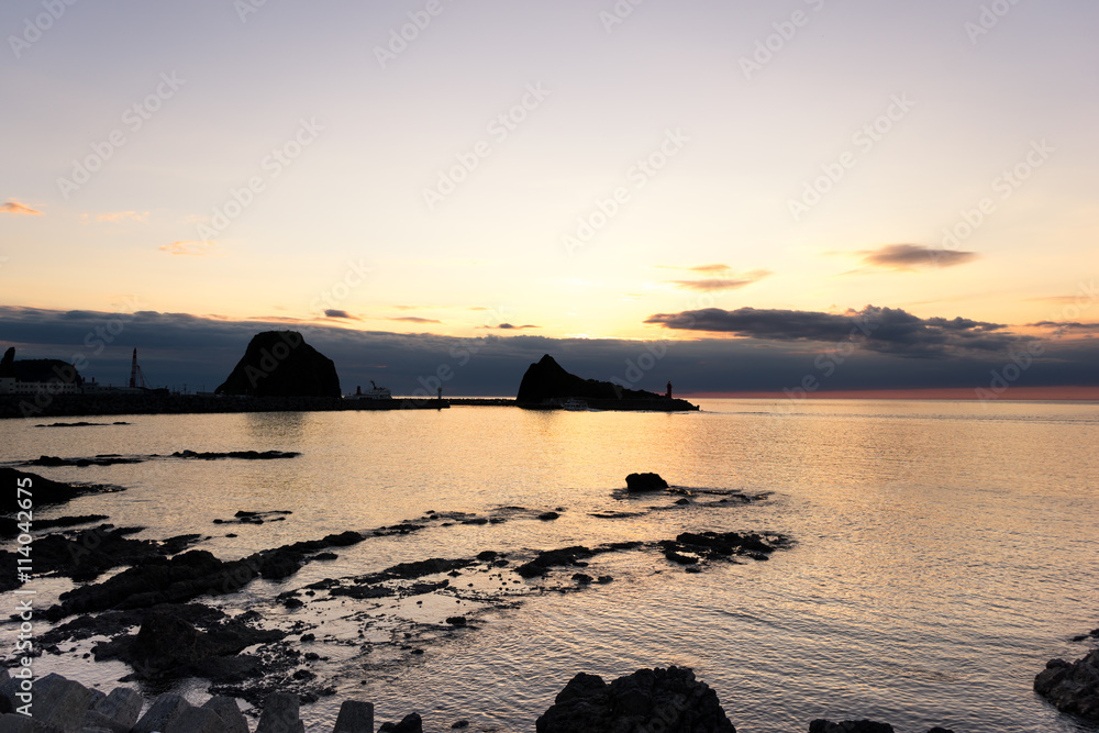 日出时宁静的海边的岩石海滩