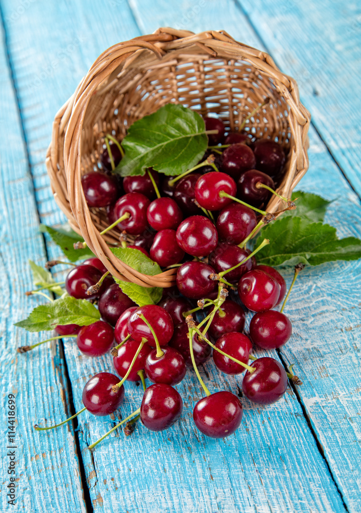 Cherries in basket, placed on old wooden planks