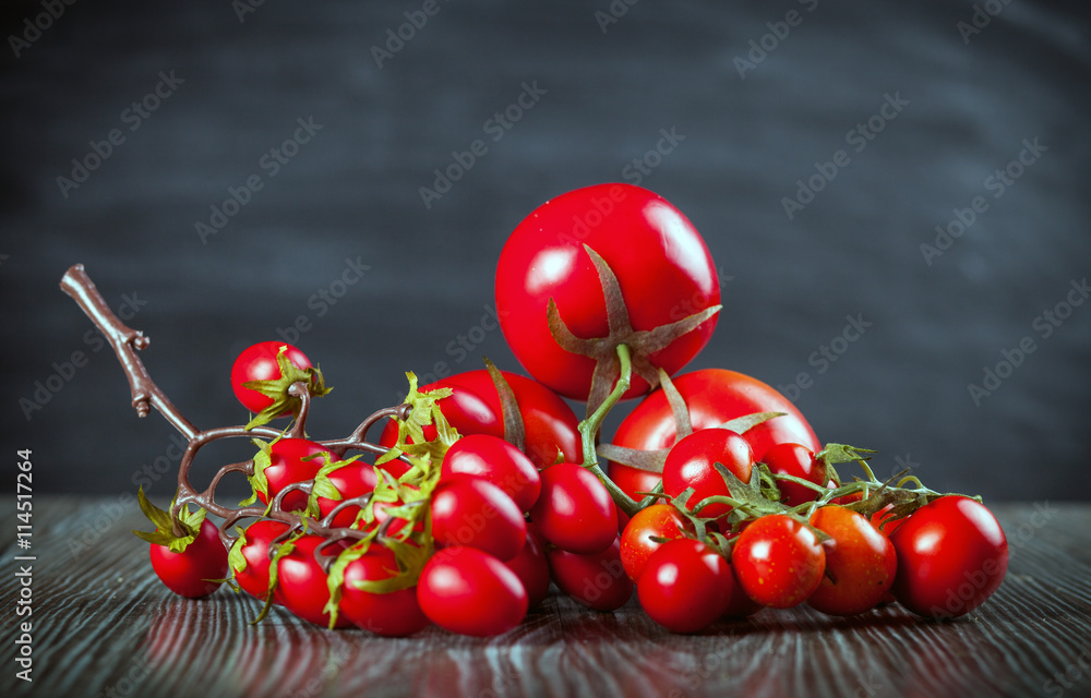 Various tomatoes on wooden table dark background front view