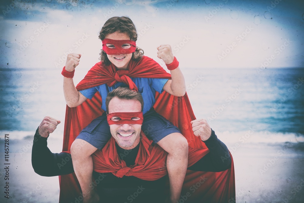 Father and son smiling while flexing muscles at sea shore