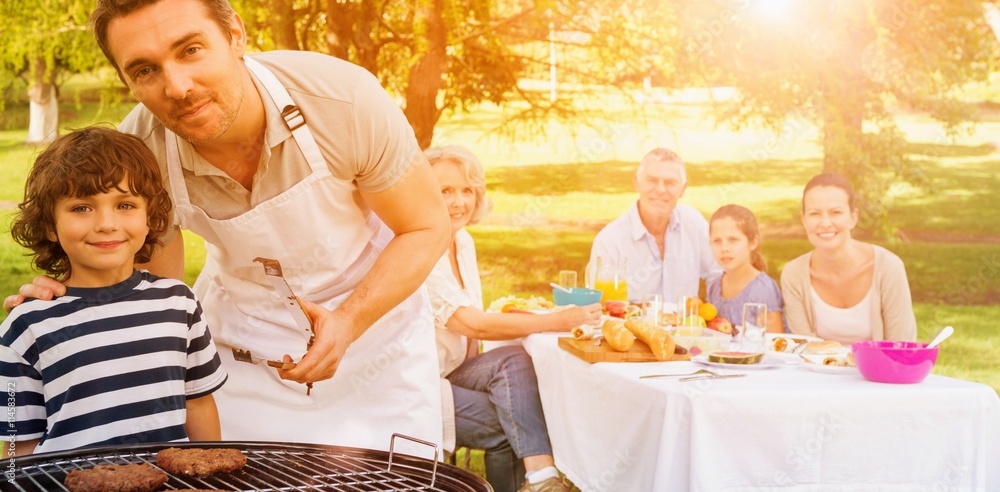 Father and son at barbecue grill with family 