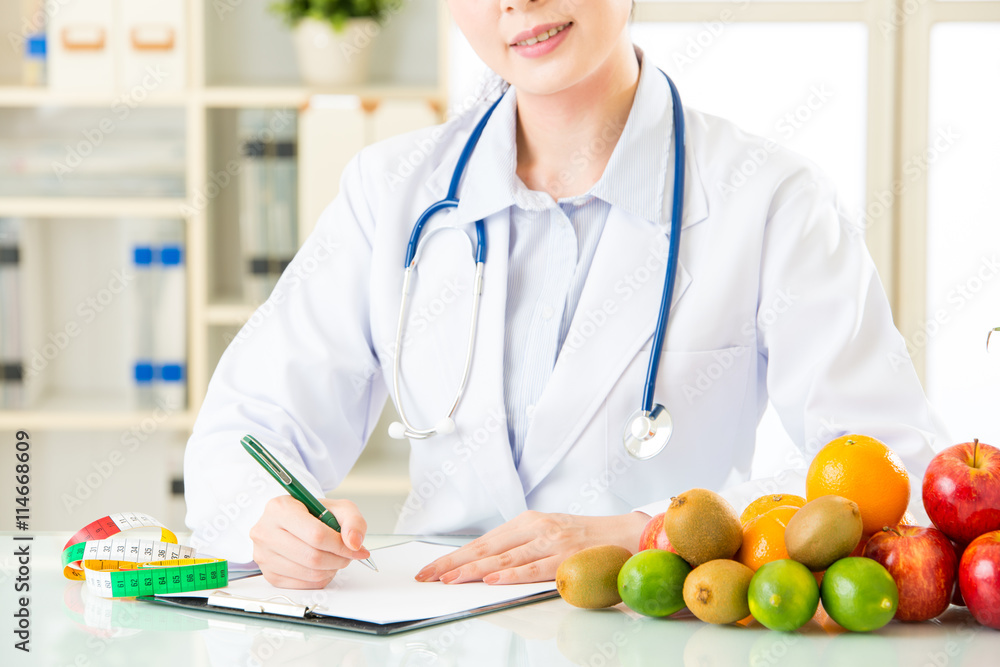 Young asian nutritionist doctor writing diet plan