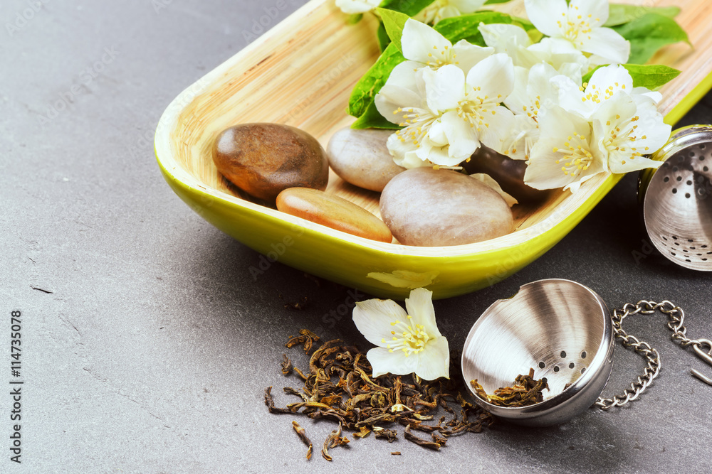 Tea infuser with dry green tea leaves and jasmine flowers