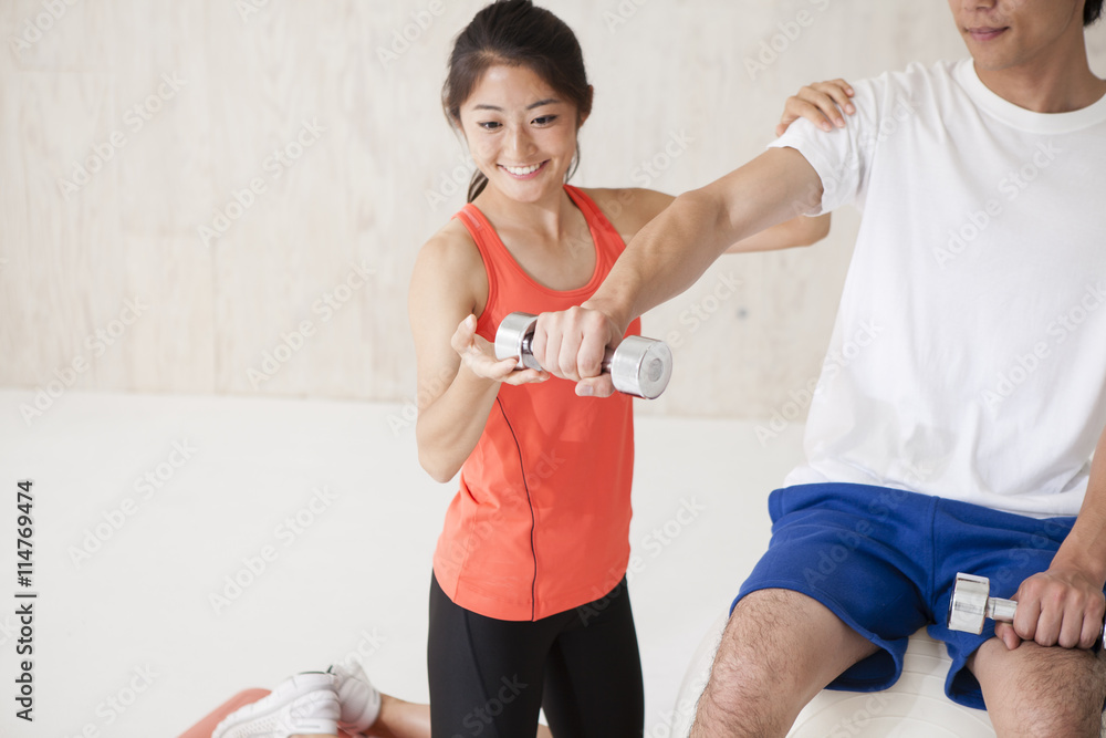 Men have a dumbbell exercise sitting on a balance ball