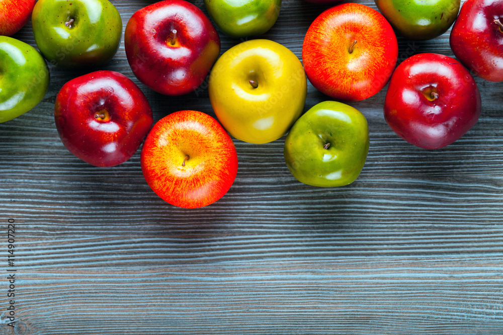 Ripe red green and yellow apples on wooden board background