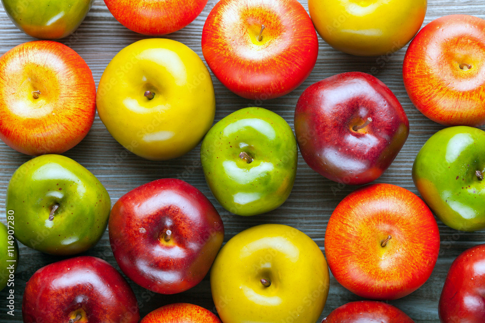 Ripe red green and yellow apples on wooden board background