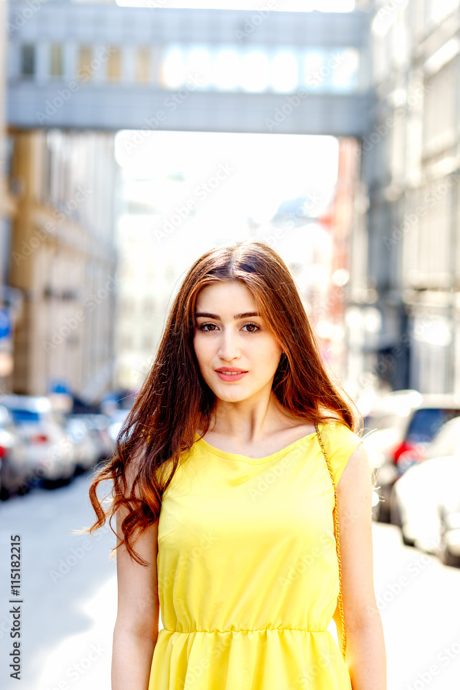 young girl on city streets in summer in yellow dress