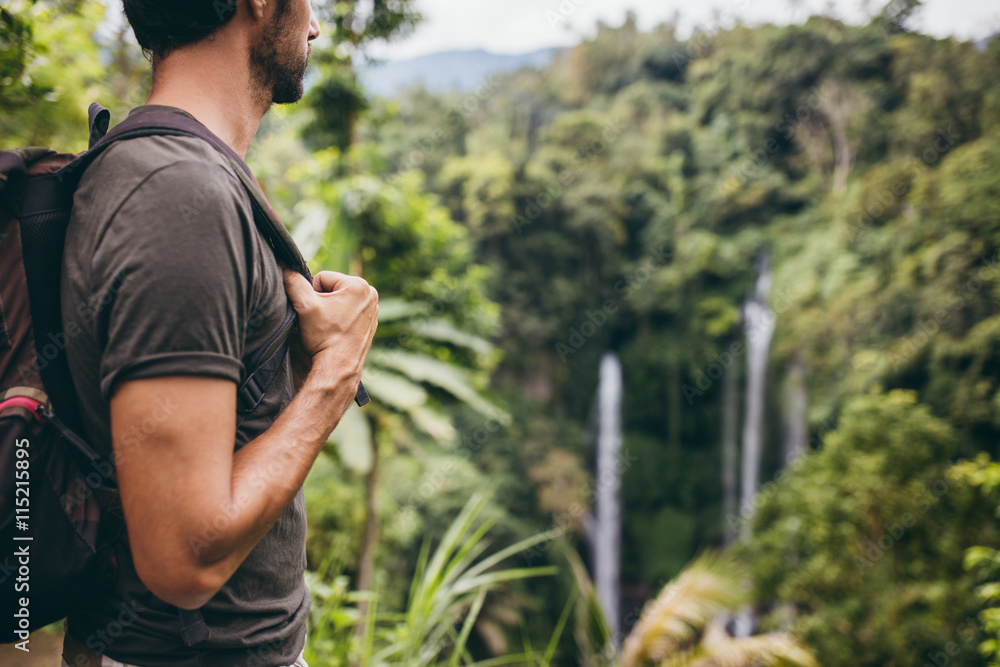 Male hiker near waterfall in forest