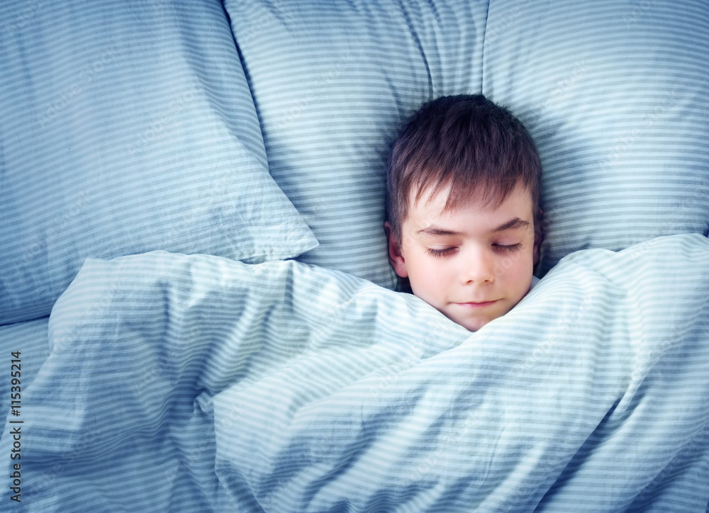 seven years old child lying in the bed with blue bedding