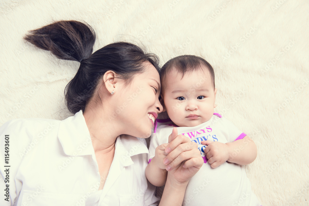 美丽妈妈在卧室里和她6个月大的婴儿玩耍的肖像，俯视图