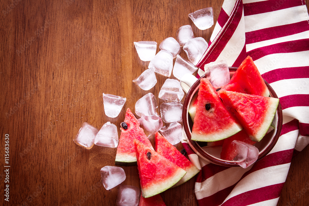 fresh sliced watermelon fruit with ice cube on brown wooden 